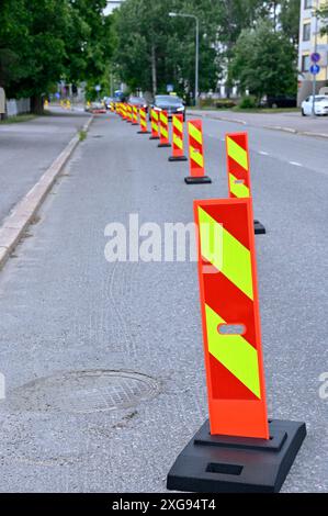 Une rangée de barrières de circulation réfléchissantes orange vif et jaune alignées le long d'une rue de la ville pour marquer une zone de construction. Les barrières sont positionnées à Banque D'Images