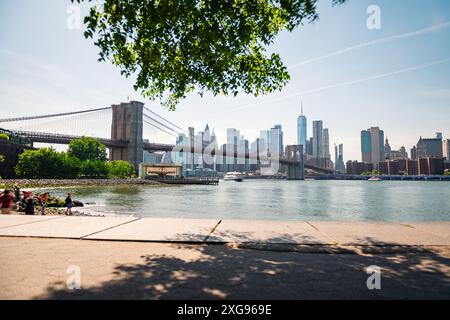 Photo longue exposition du pont de Brooklyn et des gratte-ciel de New York depuis Pebble Beach, de l'autre côté de l'East River, par un matin de printemps clair. Banque D'Images