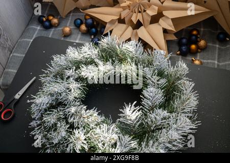 Instruction étape par étape de faire la couronne de Noël faite à la main faite de décorations festives dans les couleurs bleues et jaunes. Mains féminines créant un décor artisanal fait maison. Célébration du nouvel an. Vacances d'hiver étape 1 Banque D'Images