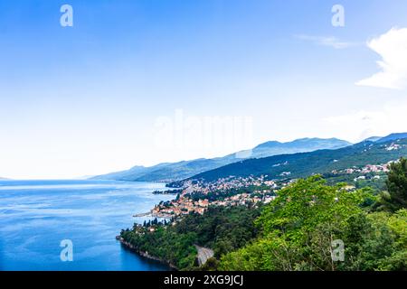 Une vue panoramique sur la côte d'Opatija, mettant en valeur la ville nichée entre des collines verdoyantes et une mer Adriatique bleu étincelant. Un ciel clair et un légume luxuriant Banque D'Images