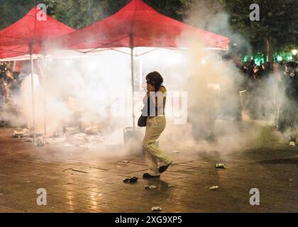 Saint Ouen, Paris, France. 7 juillet 2024. Une femme couvre le visage élevé des gaz lacrymogènes de la police. Les manifestants s'affrontent avec les forces de police à la périphérie d'un rassemblement pour la nuit des élections après les résultats du second tour des élections législatives françaises sur la place de la République. Une large coalition de gauche conduisait des élections législatives françaises serrées, devant les centristes du président et l'extrême droite, sans qu'aucun groupe ne remporte la majorité absolue, ont montré les projections. Crédit : ZUMA Press, Inc/Alamy Live News Banque D'Images