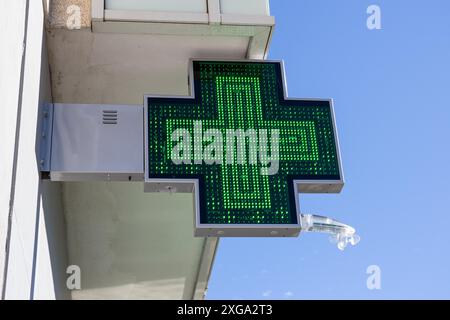 Panneau électrique de la pharmacie sur la façade du bâtiment.Croix verte éclairée Banque D'Images