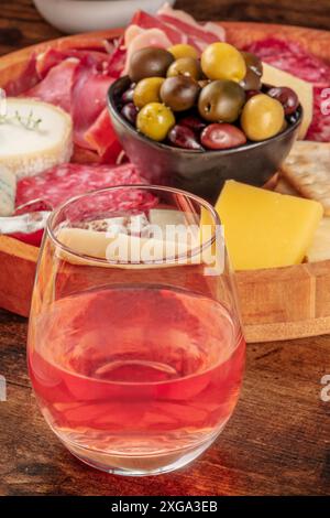 Un verre de vin rose, gros plan devant un plateau de fromage avec des olives. Un verre dans un bar avec des antipasti ou des tapas. Cuisine gastronomique Banque D'Images