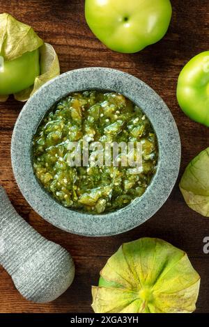 Tomatillos, tomates vertes, avec salsa verde, sauce verte, dans un molajote, Mortier mexicain traditionnel, photo sur fond de bois rustique foncé Banque D'Images