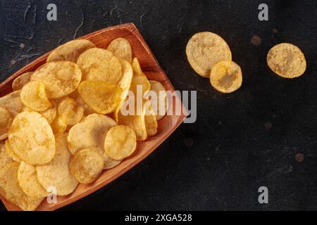 Croustilles ou chips dans un bol, prises par le haut sur fond noir avec espace de copie Banque D'Images