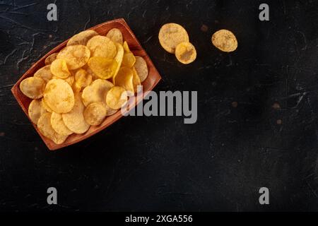 Croustilles ou chips dans un bol, au-dessus de la tête à plat, déposer la photo sur un fond noir ardoise avec un espace de copie Banque D'Images