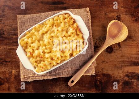 Macaroni et pâtes au fromage dans une cocotte, tiré d'en haut sur une table rustique avec une cuillère en bois Banque D'Images