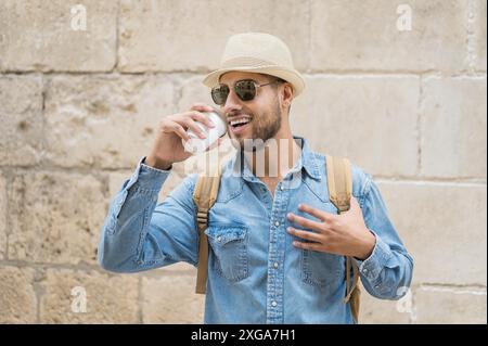 Un jeune touriste heureux avec un café à emporter et un sac à dos dans la rue. Photo de haute qualité Banque D'Images