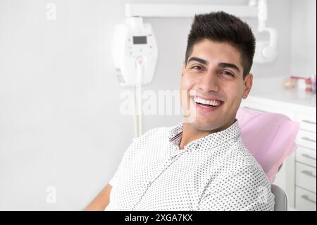 Portrait d'un beau patient positif souriant regardant la caméra, après traitement à la clinique dentaire. Photo de haute qualité Banque D'Images