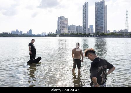 Wuhan, Chine. 07 juillet 2024. Les gens jouent dans le parc inondé de Hankou Riverbank du fleuve Yangtze. Les niveaux d'eau dans les tronçons moyen et inférieur du fleuve Yangtsé -- le plus long fleuve de Chine -- sous l'estuaire du lac Dongting, ont dépassé le seuil d'avertissement, selon le ministère des ressources en eau. Crédit : SOPA images Limited/Alamy Live News Banque D'Images