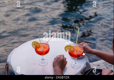 Un couple profite de son apéritif avec deux verres de spritz en bord de mer. Copier l'espace. Banque D'Images