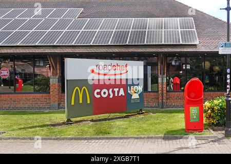 Autoroute M25 Clacket Lane Roadchef services signe et logos de marque de certaines entreprises dans la construction de panneaux solaires revêtus sur le toit journée ensoleillée dans le Surrey Angleterre Royaume-Uni Banque D'Images