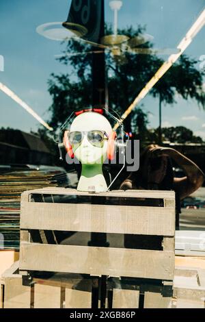 Mannequin portant des lunettes de soleil et des écouteurs devant la fenêtre du magasin Banque D'Images