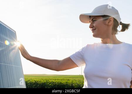 Femme touche un panneau solaire au coucher du soleil. Banque D'Images