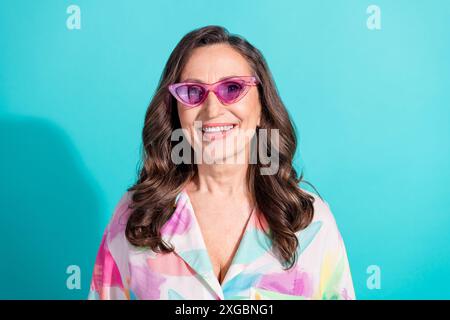 Portrait photo de vacances d'été de lunettes de soleil de femme senior attrayantes habillées élégantes vêtements colorés isolés sur fond de couleur cyan Banque D'Images