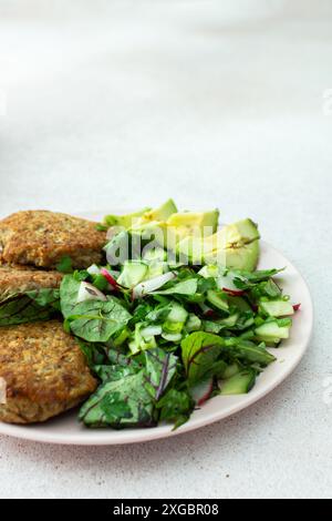 Côtelettes de quinoa et salade mixte avec avocat et radis, kiwi et eau au citron, délicieux petits déjeuners copieux, assiette végétalienne Banque D'Images