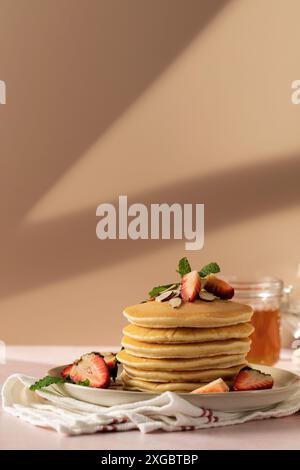 Profitez d'un merveilleux petit déjeuner avec des crêpes, des fraises et du miel sous la lumière chaude du soleil Banque D'Images