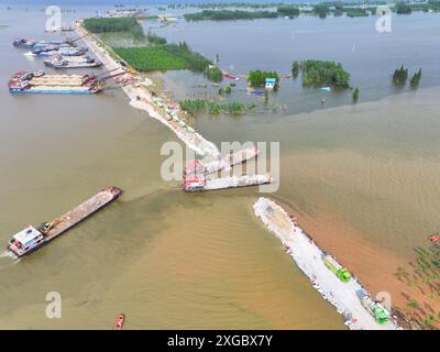 Huarong, province chinoise du Hunan. 8 juillet 2024. Une photo de drone aérien montre des sauveteurs travaillant pour bloquer la brèche de digue dans le lac Dongting dans le comté de Huarong, dans la province du Hunan, au centre de la Chine, le 8 juillet 2024. Lundi après-midi, 180,5 mètres de la brèche de 226 mètres dans la digue avaient été scellés, selon le siège de lutte contre les inondations et de secours contre la sécheresse de Yueyang. Crédit : Chen Zeguo/Xinhua/Alamy Live News Banque D'Images