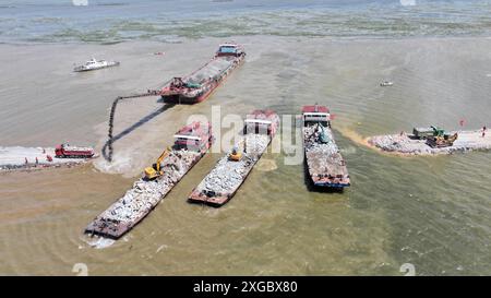 Huarong, province chinoise du Hunan. 8 juillet 2024. Une photo de drone aérien montre des sauveteurs travaillant pour bloquer la brèche de digue dans le lac Dongting dans le comté de Huarong, dans la province du Hunan, au centre de la Chine, le 8 juillet 2024. Lundi après-midi, 180,5 mètres de la brèche de 226 mètres dans la digue avaient été scellés, selon le siège de lutte contre les inondations et de secours contre la sécheresse de Yueyang. Crédit : Chen Zhenhai/Xinhua/Alamy Live News Banque D'Images