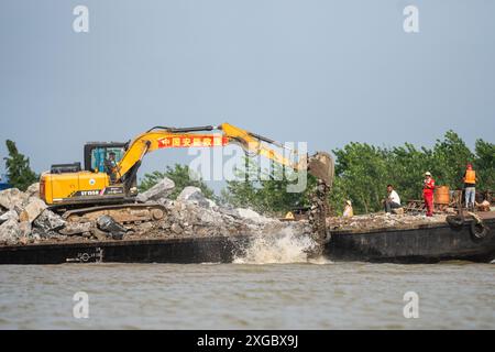 Huarong, province chinoise du Hunan. 8 juillet 2024. Les sauveteurs travaillent pour bloquer la brèche de la digue dans le lac Dongting dans le comté de Huarong, dans la province du Hunan, au centre de la Chine, le 8 juillet 2024. Lundi après-midi, 180,5 mètres de la brèche de 226 mètres dans la digue avaient été scellés, selon le siège de lutte contre les inondations et de secours contre la sécheresse de Yueyang. Crédit : Chen Sihan/Xinhua/Alamy Live News Banque D'Images