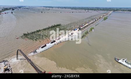 Huarong, province chinoise du Hunan. 8 juillet 2024. Une photo de drone aérien montre des sauveteurs travaillant pour bloquer la brèche de digue dans le lac Dongting dans le comté de Huarong, dans la province du Hunan, au centre de la Chine, le 8 juillet 2024. Lundi après-midi, 180,5 mètres de la brèche de 226 mètres dans la digue avaient été scellés, selon le siège de lutte contre les inondations et de secours contre la sécheresse de Yueyang. Crédit : Chen Zhenhai/Xinhua/Alamy Live News Banque D'Images