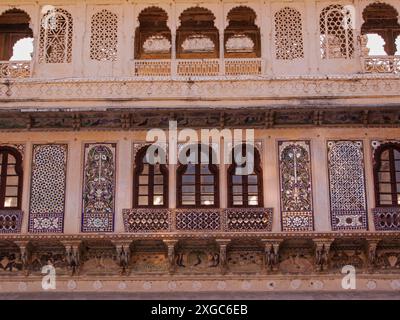 Une section de fenêtres, balcons et jalis en pierre incorporés dans le City Palace à Udaipur, Inde Banque D'Images