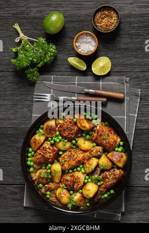 Poulet Vésuve, morceaux de poulet brun doré cuits avec des pommes de terre rôties, oignon et pois verts dans une sauce au citron au vin blanc dans un plat de cuisson sur bois foncé Banque D'Images