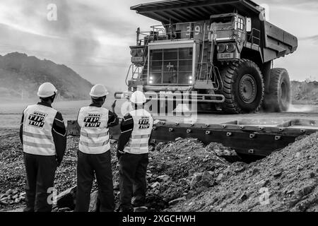 Une échelle de gris de trois inspecteurs de la sécurité minière examinant un gros camion à benne basculante transportant du minerai de palladium platine pour traitement en Afrique du Sud Banque D'Images