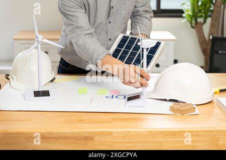 Bureau d'architectes énergie solaire alimenté Home Green pour réduire le concept de réchauffement climatique. Jeune homme d'affaires avec éolienne et panneaux solaires au bureau dans Banque D'Images