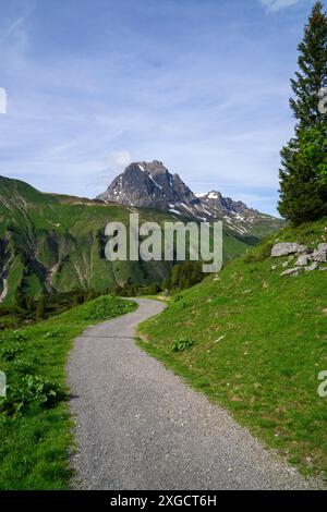 Panorama avec un banc de parc sur un sentier de randonnée avec vue sur les montagnes environnantes dans la région d'Arlberg, sommets nuageux enneigés Banque D'Images