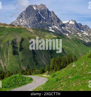 Panorama avec un banc de parc sur un sentier de randonnée avec vue sur les montagnes environnantes dans la région d'Arlberg, sommets nuageux enneigés Banque D'Images