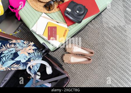 Une valise verte ouverte avec différents vêtements pour voyager à la maison. Accessoires de plage dans une valise ouverte. Sac de voyage avec roulettes. Vêtements différents. Banque D'Images