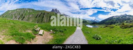 Panorama avec un banc de parc sur un sentier de randonnée avec vue sur les montagnes environnantes dans la région d'Arlberg, sommets nuageux enneigés Banque D'Images