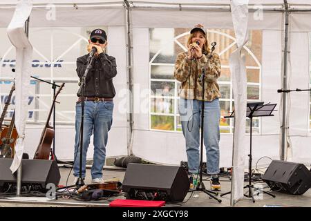 Chanteuse et harmoniciste masculin sur scène. Concert de musique live montrant deux membres du groupe sur scène avec des moniteurs et des guitares sur des stands. Banque D'Images