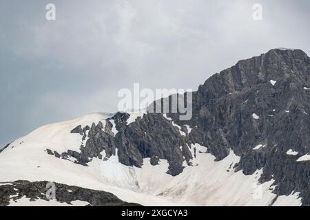 Champ de neige dans la montagne, corniches, déneigements sur le pic, couverture de neige en surplomb est un danger d'avalanches, de chute possible de neige, de froid de neige Banque D'Images