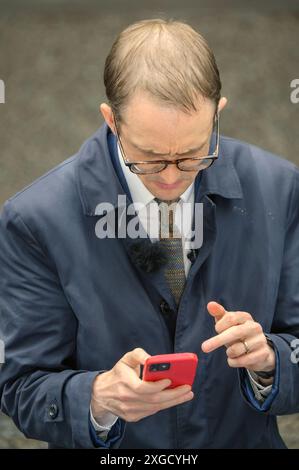 Chris Mason - BBC News Political Editor - à Downing Street sur son téléphone portable le lendemain de la victoire des travaillistes aux élections législatives, le 5 juillet 2024. Banque D'Images