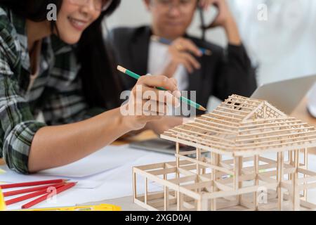 Architectes travaillant sur un modèle de maison dans un bureau créatif. Deux jeunes gens d'affaires ayant une discussion sur un nouveau projet de design, travaillant sur un archite Banque D'Images