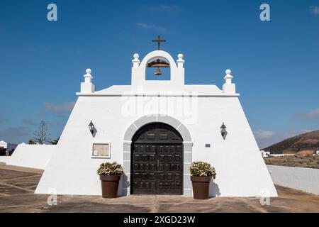 Couleur blanche traditionnelle de la façade du bâtiment. Petite église avec un beffroi et une croix. Masdache, Lanzarote, Îles Canaries, Espagne. Banque D'Images