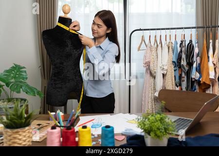 Concepteur de costumes féminin mature asiatique mesurer la taille de la forme de la marionnette de dressing dans un studio et travaille avec des vêtements, collection de design de mode, professionnona Banque D'Images