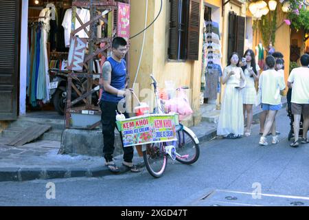 Hoi an, Vietnam 7 juillet 2024 : hawker vend sa crème glacée fumée dans la vieille ville de Hoi an à vélo Banque D'Images