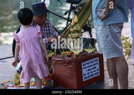 Hoi an, Vietnam 7 juillet 2024 : le colporteur vend la sauterelle, faite par tissage d'herbe. le tissage de l'herbe est une compétence traditionnelle de tissage de l'art. Banque D'Images