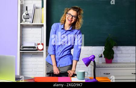 Concept d'éducation. Heureux professeur d'école, docent ou éducateur donnant des leçons aux élèves en classe. Jeune professeur ou tuteur d'université dans des lunettes près de bla Banque D'Images