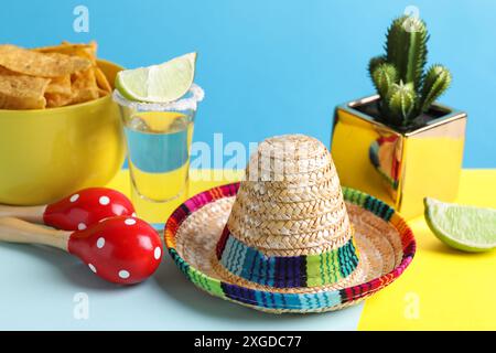 Chapeau sombrero mexicain, cactus, croustilles de nachos, maracas et tequila sur fond bleu clair Banque D'Images