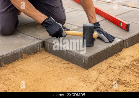 ouvrier installant des dalles de pavage en béton sur des fondations en sable Banque D'Images