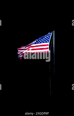 Drapeau américain déchiqueté sur un poteau dans un fond noir avec espace de copie, vertical Banque D'Images