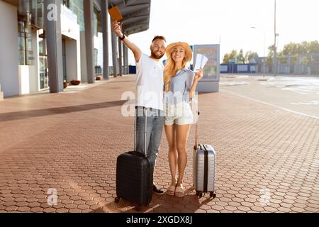 Couple enthousiaste montrant des billets près de l'aéroport moderne Banque D'Images