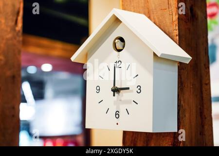 Horloge Cuckoo blanche sur un mur de support de pilier en bois Banque D'Images