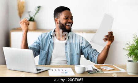 Black excité businessman checking rapports financiers et des succès à célébrer Banque D'Images