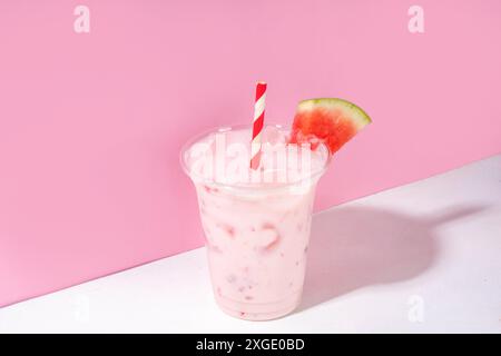 Délicieux milkshake sucré à la pastèque ou cocktail de slushie crémeux, garni de tranche de pastèque dans une tasse en plastique, espace de copie Banque D'Images