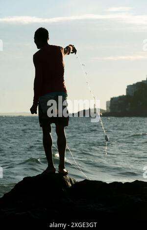 Salvador, Bahia, Brésil - 17 mai 2019 : pêcheur, en silhouette, est vu pêcher avec une ligne de nylon sur la plage de Rio Vermelho dans la ville de Salvador, Bahia Banque D'Images